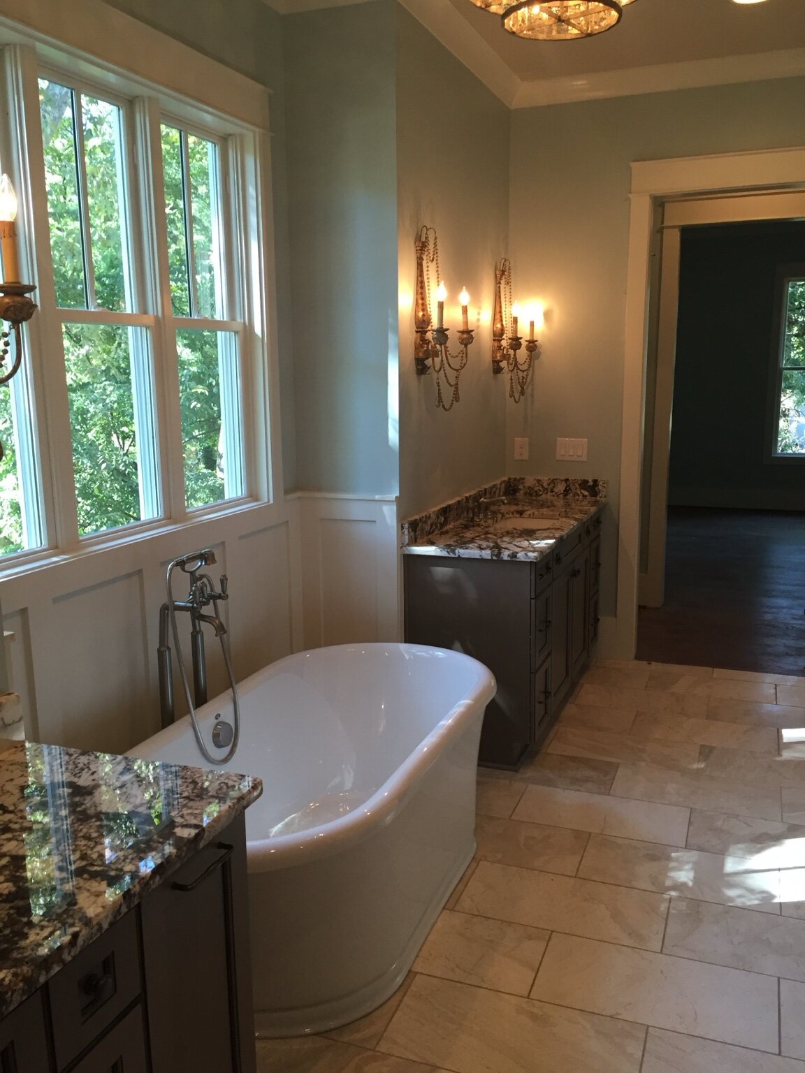 Primary bathroom with freestanding tub, stone floor, and paneled walls