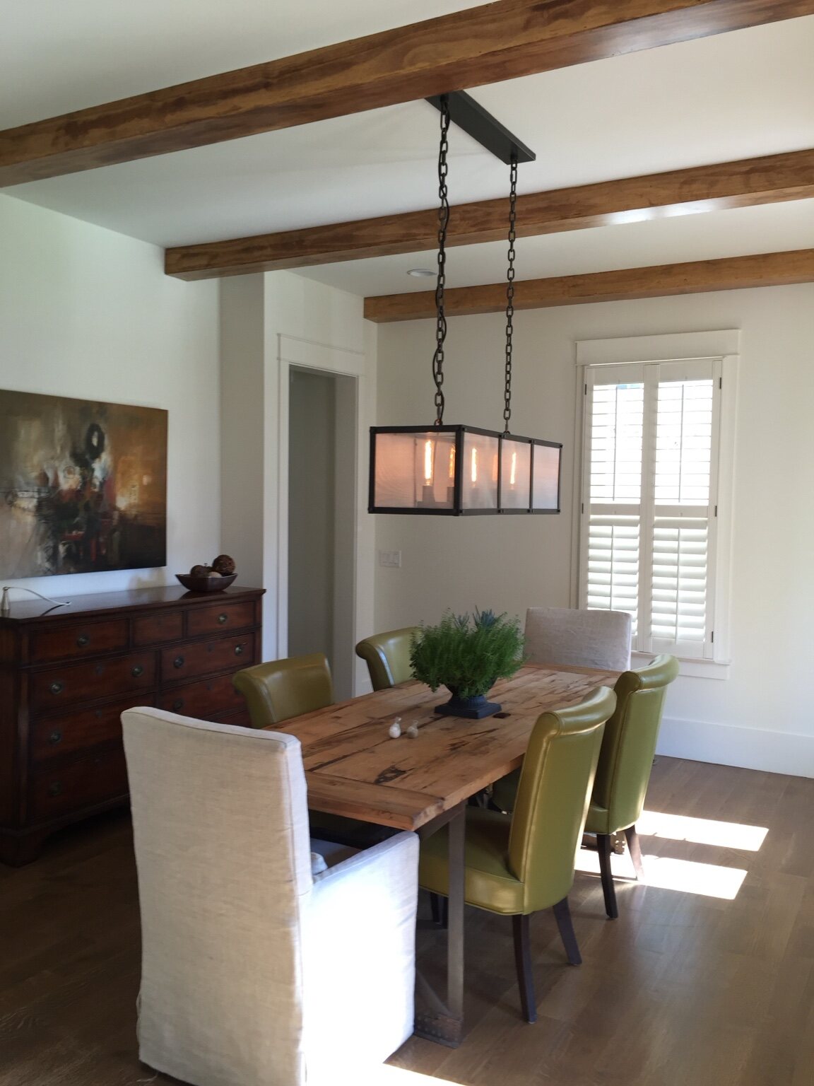 Dining room with exposed beams and a linear iron chandelier