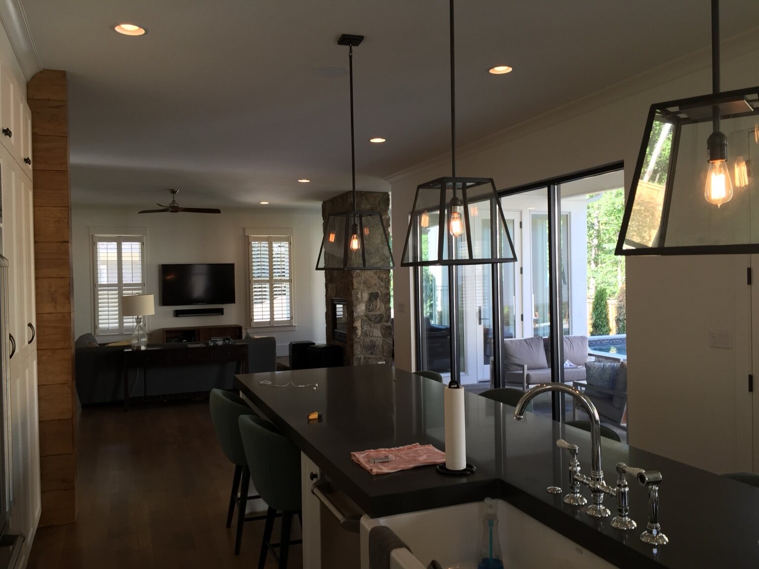 Custom kitchen with dark stone counters, tailored cabinetry, and oversized pendants