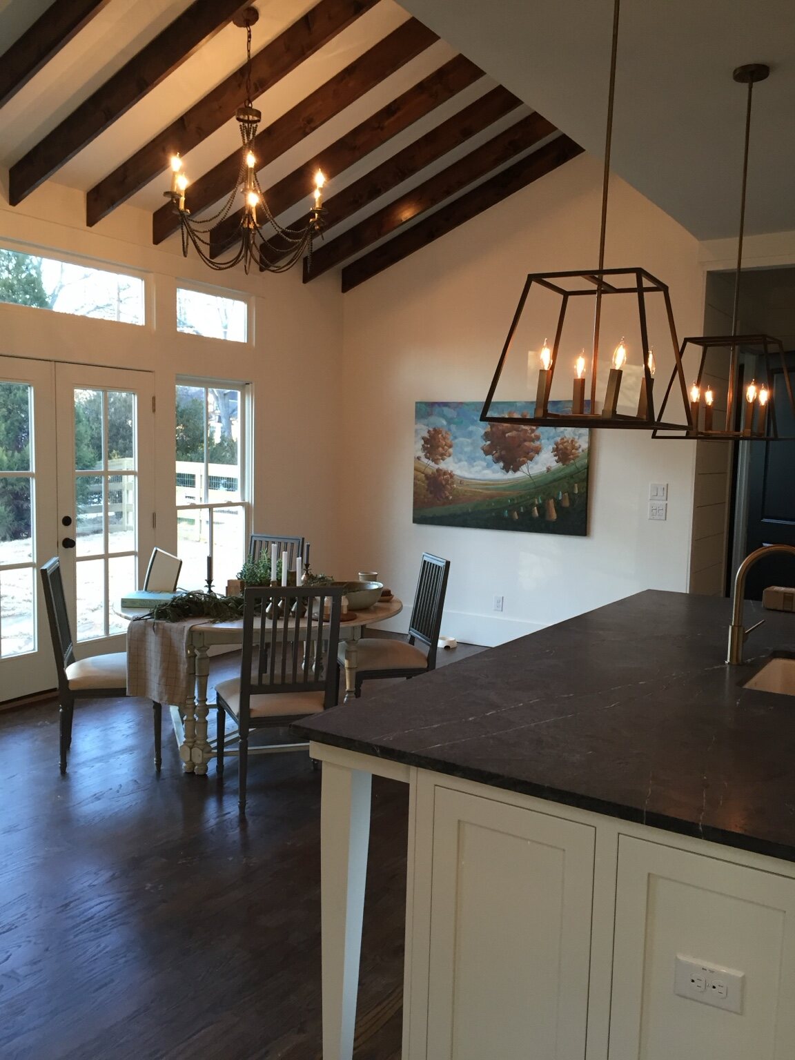 Vaulted dining room beside a custom kitchen with exposed dark wood rafters