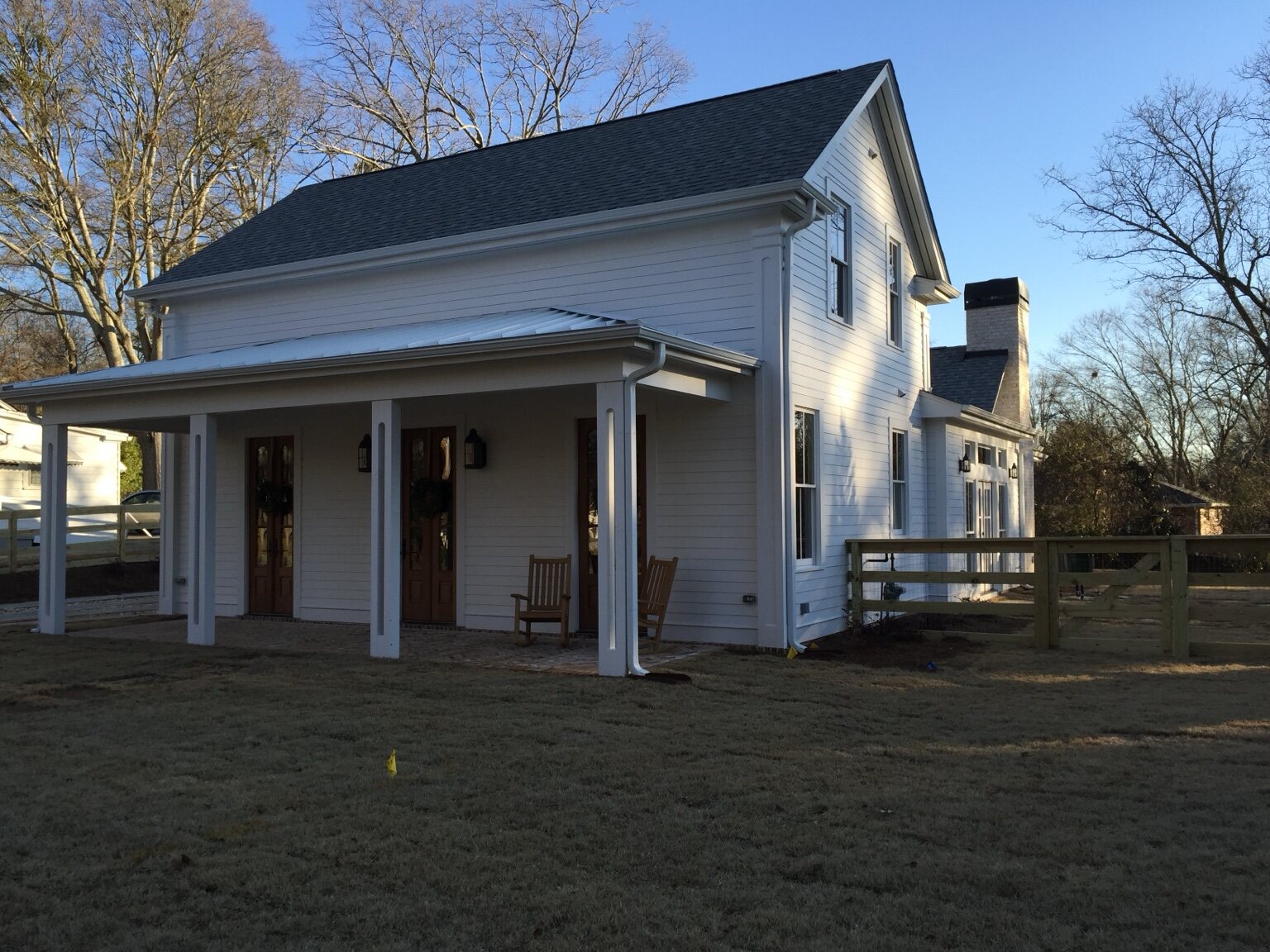 Rear elevation of a white custom residence with a deep covered porch