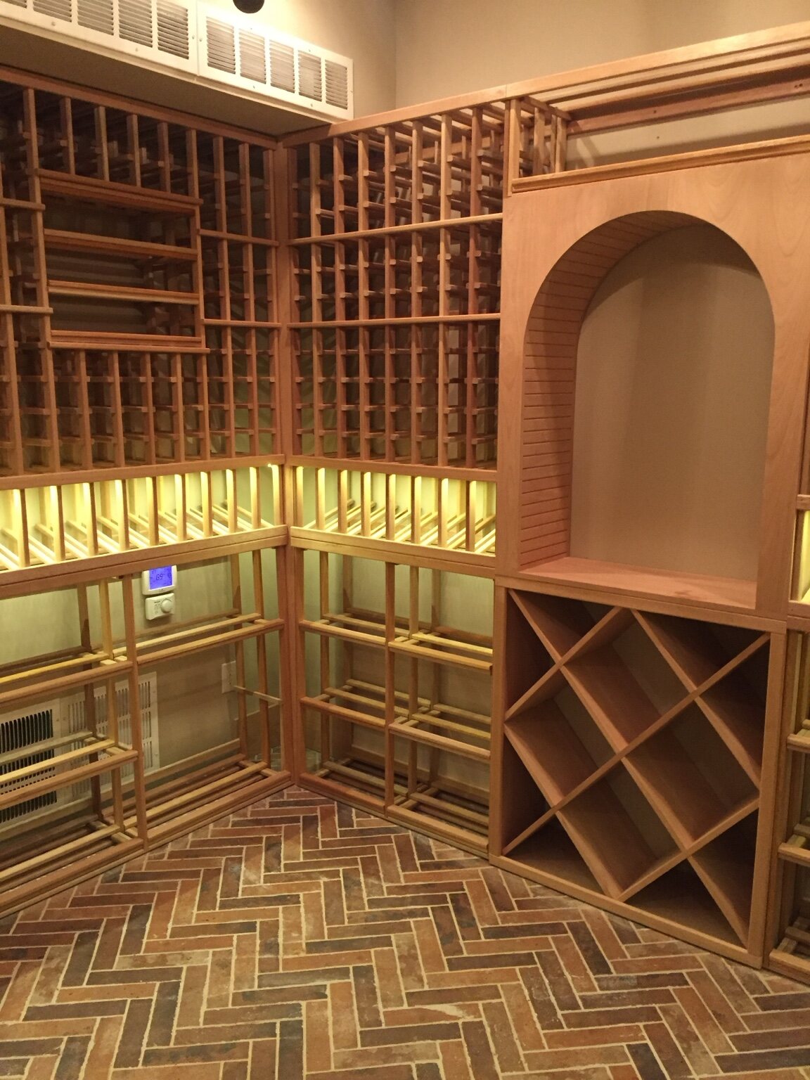 Custom residential wine room with illuminated bottle storage and a herringbone brick floor